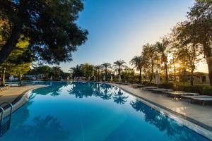 - une piscine avec des palmiers et de l'eau bleue dans l'établissement IC Hotels Green Palace - Kids Concept, à Lara