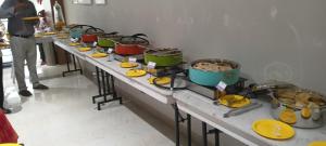 a row of buffet tables with pots and pans at TM INN Hotel in Kanchipuram