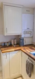 a kitchen with white cabinets and a counter top at Woodcutters Cottage, Northumberland in Haltwhistle