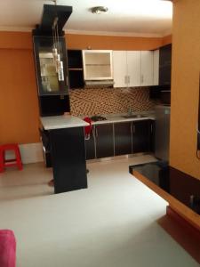 a kitchen with black cabinets and a white counter top at Lily's Room in Cibubur