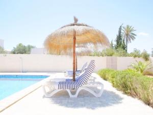a chair and an umbrella next to a swimming pool at Dar Elyas in Mezraya