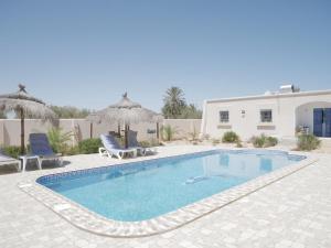 a swimming pool with two chairs and a building at Dar Elyas in Mezraya