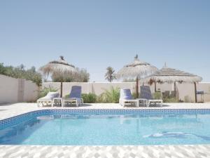 a swimming pool with chairs and umbrellas at Dar Elyas in Mezraya
