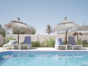 a group of chairs and umbrellas next to a swimming pool at Dar Elyas in Mezraya