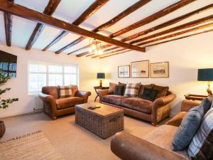 a living room with leather furniture and a wooden ceiling at Well Cottage in Grimston