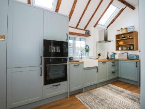 a kitchen with white cabinets and black appliances at Well Cottage in Grimston