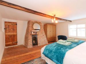 a bedroom with a bed and a brick fireplace at Well Cottage in Grimston
