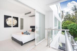 a white bedroom with a bed and a balcony at sunset plaza condominium by Ryan, 600 meters to Karon Beach in Karon Beach
