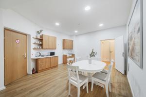 a kitchen and dining room with a white table and chairs at Central City Rooms by HOME2 in Vienna