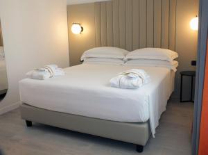 una camera da letto con un letto bianco e asciugamani di BB Hotels Smarthotel Derose a Firenze