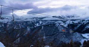 a ski lift flying over a snow covered mountain at Appartamenti al Prel in Prato Nevoso