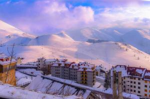 Una ciudad en la nieve con montañas en el fondo en Appartamenti al Prel, en Prato Nevoso