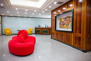 a living room with a red chair and a flat screen tv at Best Western Hotel Ferrari in Nola