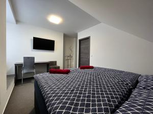 a bedroom with a bed with red pillows and a desk at Penzion Sýpka in Jablŭnka