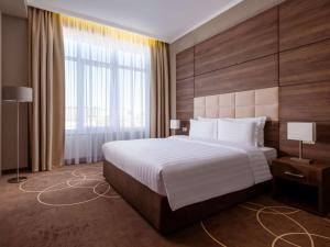 a bedroom with a large bed and a large window at Movenpick Resort & SPA Anapa Miracleon in Anapa