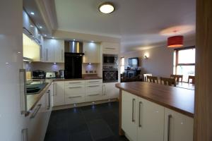 cocina con armarios blancos y encimera de madera en Wesdale, Stromness - 3 Bedroom Holiday Cottage en Orkney