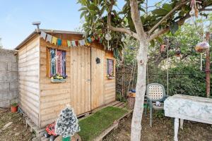 a small wooden cabin with a table and a tree at Casita Rural La Piñera in Los Realejos