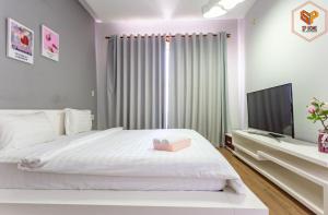 een slaapkamer met een wit bed en een flatscreen-tv bij Sunrise City in Ho Chi Minh-stad