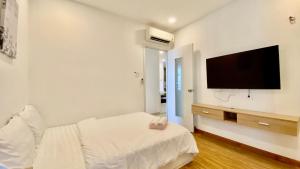 Dieses weiße Zimmer verfügt über ein Bett und einen Flachbild-TV. in der Unterkunft Sunrise City 3 Bed Room in Ho-Chi-Minh-Stadt