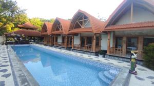 a hotel with a swimming pool in front of a building at Kristal Garden in Sekotong