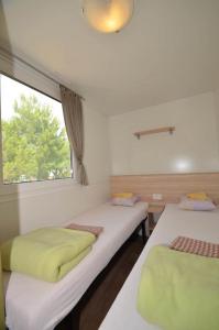 two beds in a room with a window at Campsite Pisak - mobile homes by the sea in Seline