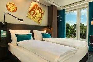two beds in a room with a window at Motel One Warsaw-Chopin in Warsaw