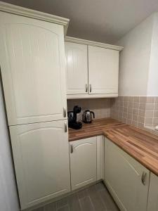 a kitchen with white cabinets and a wooden counter top at Gated Stunning Period Studio in Vibrant Bristol in Bristol