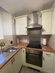 a kitchen with white cabinets and a sink and a stove at Gated Stunning Period Studio in Vibrant Bristol in Bristol