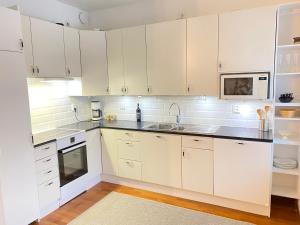 a kitchen with white cabinets and a sink and a microwave at Family city apartment Helsinki in Helsinki