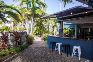 a bar with stools in front of a blue building with palm trees at Renovated 2 Bedroom Ground Level Villa in Noosaville in Noosaville