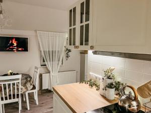 a kitchen with white cabinets and a table with a fireplace at Guest house Laimes taure in Vabole