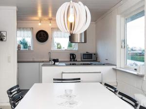 ヒュールスミンネにある6 person holiday home in Juelsmindeのキッチン(白いテーブル、椅子、シャンデリア付)