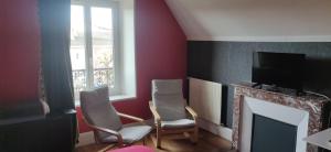 ein Wohnzimmer mit 2 Stühlen und einem Kamin in der Unterkunft Calme et repos en ville in Châlons-en-Champagne