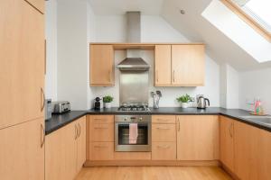 cocina con armarios de madera y horno con fogones en The Modern Mill Apartment, en Edimburgo