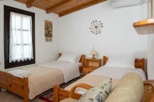 two beds in a room with a couch and a window at Kalimera Villa, Afissos Pelion in Afissos