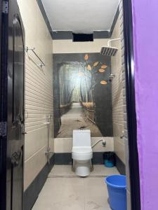 uma casa de banho com WC e uma pintura na parede em Riru girlstay em Patna