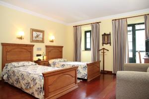 a hotel room with two beds and a chair at Posada Casa de don Guzman in Vega de Pas