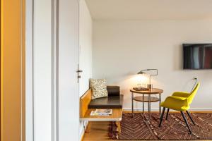 une chambre avec une table et une chaise jaune dans l'établissement Krafft Basel, à Bâle