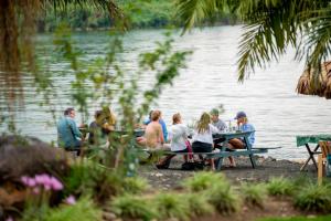 a group of people sitting at picnic tables by the water at Paradis Malahide in Gisenyi