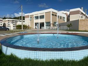 una piscina con 2 fuentes de agua frente a un edificio en Apto térreo 2/4 a poucos metros da praia, en Ilhéus