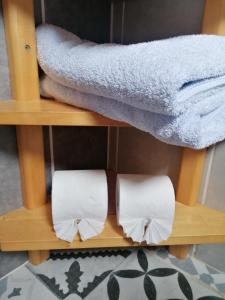 deux rouleaux de papier toilette sur une étagère avec des serviettes dans l'établissement Chez les Martin, à Castelnau-de-Médoc