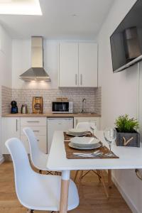 uma cozinha branca com uma mesa e cadeiras brancas em Granaxperience Apartamentos La Maleta em Granada
