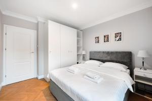 ein weißes Schlafzimmer mit einem großen Bett mit weißer Bettwäsche in der Unterkunft Stara Praga Superior Apartment in Warschau