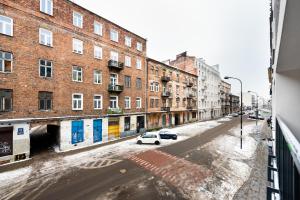 ein weißes Auto, das auf einer Stadtstraße mit Gebäuden parkt in der Unterkunft Stara Praga Superior Apartment in Warschau