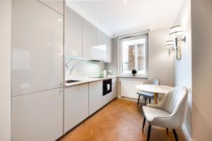 華沙的住宿－Stara Praga Superior Apartment，厨房配有白色橱柜和桌椅