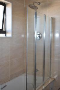 a shower with a glass door in a bathroom at Scenery Maqalika Guesthouse in Maseru