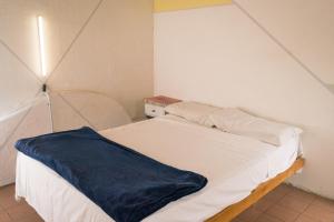 a white bed with a blue blanket on top of it at Freedom Hostel in Rosario +47 photos
