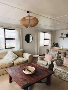 - un salon avec une table, un canapé et des chaises dans l'établissement Sweet & Simple Beach Cottage, à Jeffreys Bay