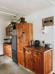 a kitchen with wooden cabinets and a black refrigerator at Sweet & Simple Beach Cottage in Jeffreys Bay