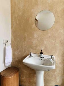 W łazience znajduje się biała umywalka i lustro. w obiekcie Sweet & Simple Beach Cottage w mieście Jeffreys Bay